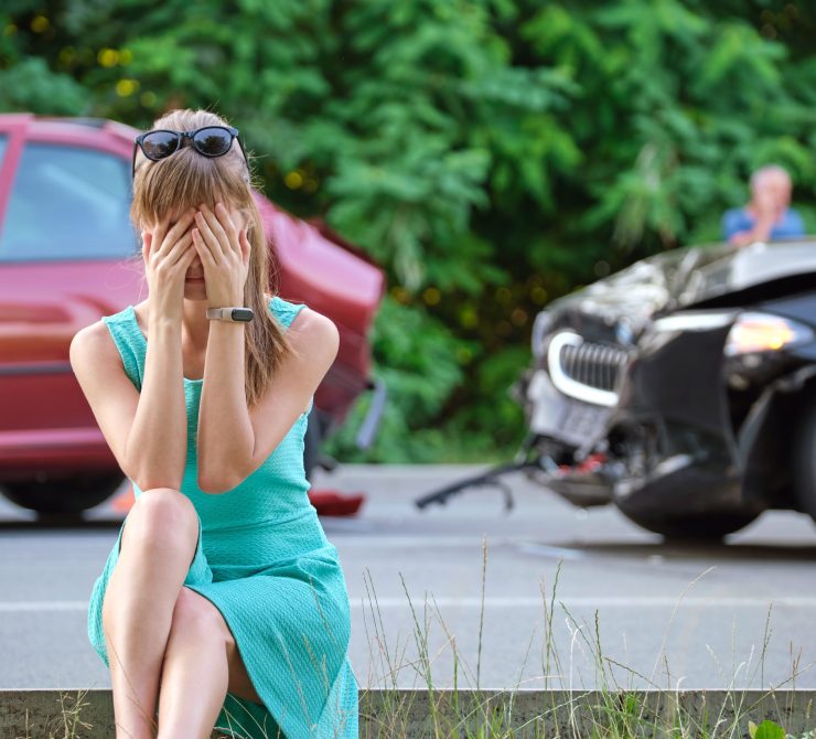 Stressed woman driver sitting on street side shocked after car accident. Road safety and insurance concept.